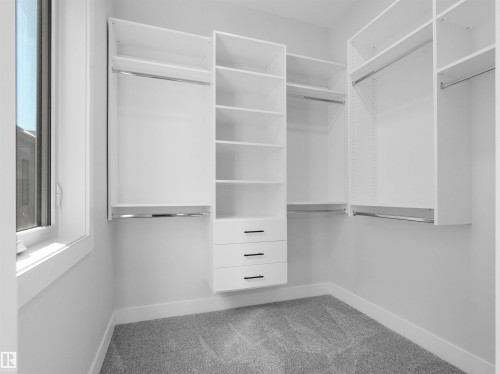 Custom built-in closet system featuring white shelving, multiple hanging rods, and integrated drawers with dark hardware - 6722 Crawford Way, Edmonton, AB - Indoor With Storage