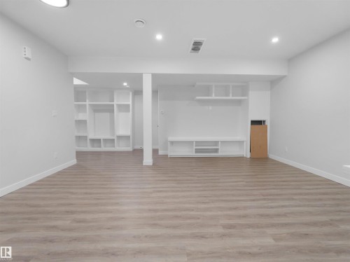 Spacious room featuring wood-finish flooring, recessed lighting, and built-in shelving - 6722 Crawford Way, Edmonton, AB - Indoor Photo Showing Other Room