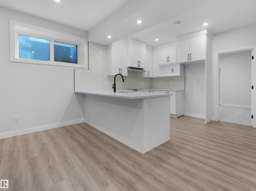 Kitchen area featuring white cabinetry, a light-toned countertop, and a white tile backsplash - 6722 Crawford Way, Edmonton, AB - Indoor Photo Showing Kitchen