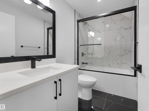 Modern bathroom featuring a white vanity with integrated sink, matte black hardware, and a framed mirror with integrated lighting - 6722 Crawford Way, Edmonton, AB - Indoor Photo Showing Bathroom