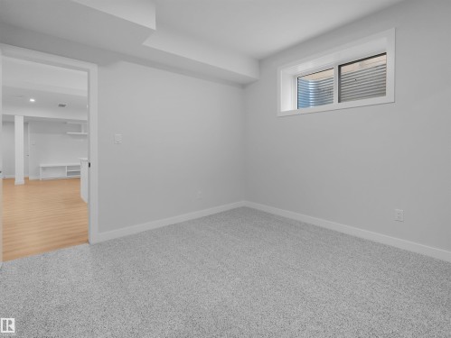 Carpeted room featuring a window with a white frame and a light-filtering blind - 6722 Crawford Way, Edmonton, AB - Indoor Photo Showing Other Room