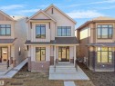 Contemporary two-story residence featuring light-colored siding, a prominent gabled roofline, and dark-framed windows - 6722 Crawford Way, Edmonton, AB  - Outdoor With Facade 
