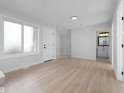 Spacious room featuring light wood-finish flooring, white trim, and light gray walls - 6722 Crawford Way, Edmonton, AB - Indoor Photo Showing Other Room