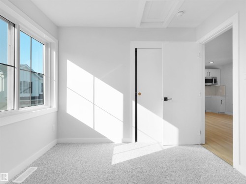 Light gray carpeted room featuring a white trim window and white walls - 6722 Crawford Way, Edmonton, AB - Indoor Photo Showing Other Room