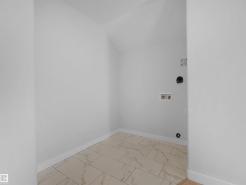 Dedicated utility space featuring light-toned tile flooring, clean white walls, and essential appliance hookups - 6722 Crawford Way, Edmonton, AB - Indoor Photo Showing Other Room