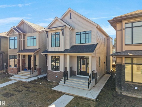 Contemporary two-story residence featuring light-colored siding, a dark roof, and black-framed windows - 6722 Crawford Way, Edmonton, AB - Outdoor With Facade