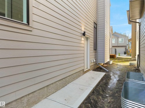Exterior wall with horizontal siding and a concrete walkway - 6722 Crawford Way, Edmonton, AB - Outdoor With Exterior