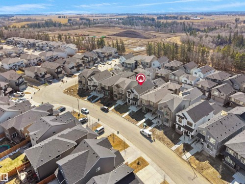 Aerial overview of a residential development featuring uniform contemporary homes with dark shingle roofs - 6722 Crawford Way, Edmonton, AB - Outdoor With View