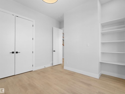 Room featuring light wood-finish flooring, white walls, and built-in shelving - 6722 Crawford Way, Edmonton, AB - Indoor Photo Showing Other Room