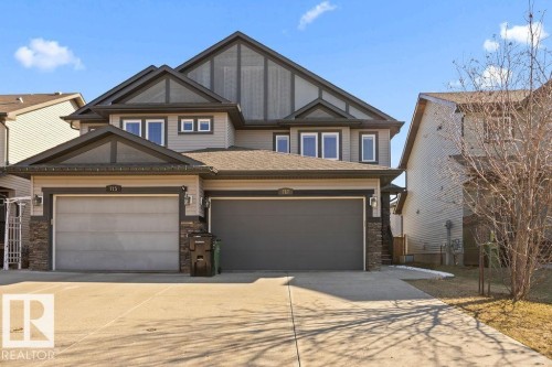 Two-story residence featuring a multi-gable roofline, neutral-toned siding, and stone veneer accents - Edmonton, AB - Outdoor With Facade