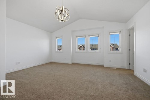 Spacious room with vaulted ceilings and a contemporary chandelier - Edmonton, AB - Indoor Photo Showing Other Room