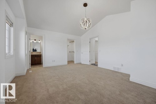 Spacious room featuring carpeting, a vaulted ceiling, and a contemporary chandelier - Edmonton, AB - Indoor Photo Showing Other Room