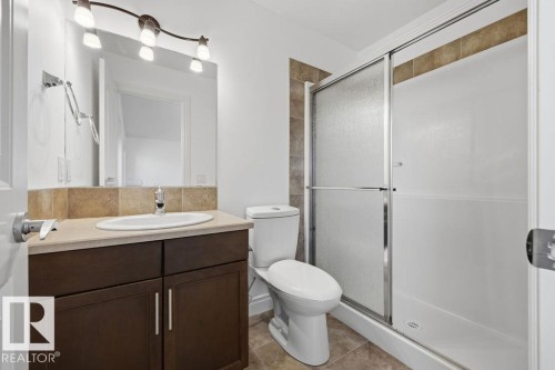 Bathroom featuring a dark wood-finish vanity with a light countertop and undermount sink, a tiled backsplash, and a large wall mirror - Edmonton, AB - Indoor Photo Showing Bathroom