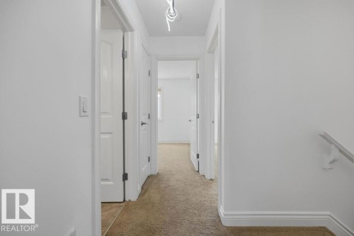 Hallway featuring light beige carpet flooring, white painted walls, and white trim molding - Edmonton, AB - Indoor Photo Showing Other Room