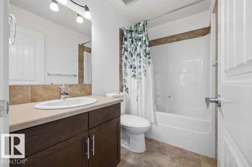 Bathroom featuring a dark wood vanity with brushed nickel hardware, a light-colored countertop, and an integrated sink with a chrome faucet - Edmonton, AB - Indoor Photo Showing Bathroom