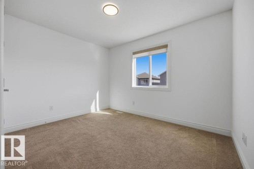 Neutral tone carpet flooring, white painted walls, and a single window with a roller shade - Edmonton, AB - Indoor Photo Showing Other Room