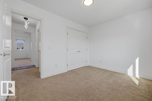 Carpeted interior room featuring white walls, a flush-mount ceiling light, and a double-door closet with paneled doors - Edmonton, AB - Indoor Photo Showing Other Room
