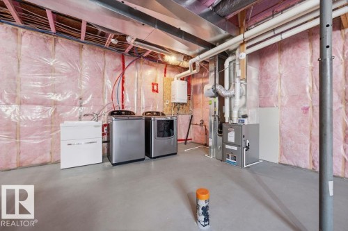 Utility space featuring exposed ceiling joists, insulated walls, concrete flooring, laundry sink, and water heater - Edmonton, AB - Indoor Photo Showing Basement