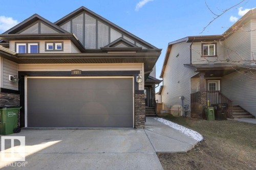 Exterior showcasing a prominent garage door, stone accents, and varied siding - Edmonton, AB - Outdoor With Facade