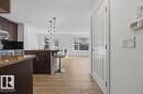 Open-concept kitchen featuring dark wood cabinetry, stainless steel appliances, and a dark tile backsplash - Edmonton, AB  - Indoor Photo Showing Kitchen 