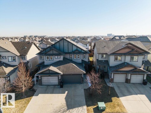 Contemporary two-story residence featuring a dark gray garage door, light gray exterior siding, and a dark shingle roof - Edmonton, AB - Outdoor With Facade