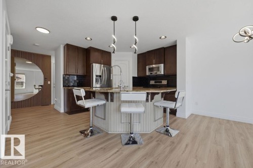 Kitchen with wood-finish flooring, dark wood cabinetry, and stainless steel appliances - Edmonton, AB - Indoor Photo Showing Kitchen With Stainless Steel Kitchen With Upgraded Kitchen