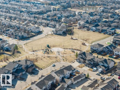 Aerial perspective of a developed residential area featuring a central park space with walking paths and recreational equipment - Edmonton, AB - Outdoor With View