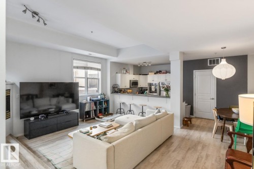 Open-concept living space featuring wood-finish flooring, a contemporary track light fixture, and a window with blinds - 109 10728 82 Avenue, Edmonton, AB - Indoor Photo Showing Living Room