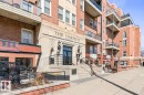 Brick-clad building facade featuring stone accents, multiple balconies with glass railings, and ground-level commercial spaces - 109 10728 82 Avenue, Edmonton, AB  - Outdoor With Facade 