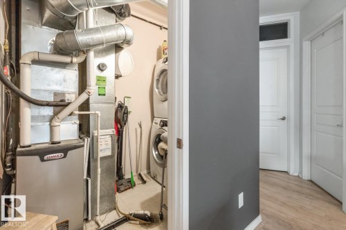 Dedicated utility space featuring a stacked washer and dryer, a furnace with visible ductwork, and light-toned flooring - 109 10728 82 Avenue, Edmonton, AB - Indoor Photo Showing Basement