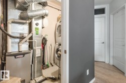 Dedicated utility space featuring a stacked washer and dryer, a furnace with visible ductwork, and light-toned flooring - 