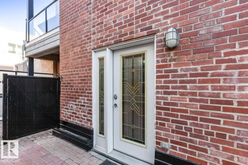 Brick facade featuring a transom window, decorative glass entry door, and exterior sconce lighting - 109 10728 82 Avenue, Edmonton, AB - Outdoor
