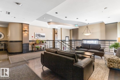 Lobby seating area featuring dark wood-finish flooring, recessed lighting, a modern chandelier, and a metal railing system - 109 10728 82 Avenue, Edmonton, AB - Indoor