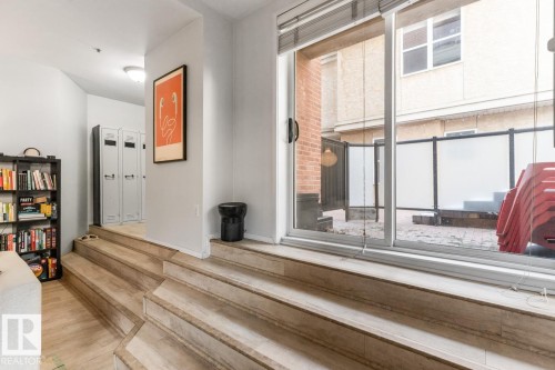 Sliding glass door opening to an outdoor patio with brick pavers and privacy screens - 109 10728 82 Avenue, Edmonton, AB - Indoor Photo Showing Other Room