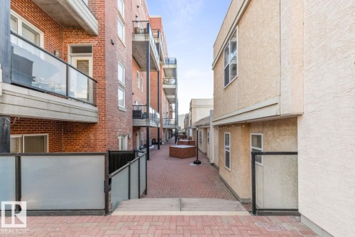 Brick paver pathway surrounded by multi-story buildings featuring brick and stucco exteriors - 109 10728 82 Avenue, Edmonton, AB - Outdoor With Exterior