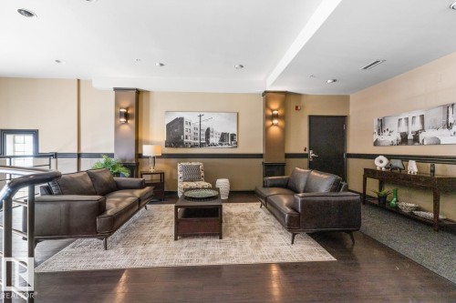 Upper-level lounge area featuring dark wood-finish flooring, recessed lighting, and wall-mounted sconces - 109 10728 82 Avenue, Edmonton, AB - Indoor Photo Showing Other Room