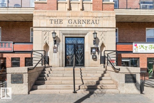 Building facade featuring a stone entryway with "THE GARNEAU" inscription, brick upper levels, a multi-step staircase, wrought iron handrails, and a glass-paneled entry door - 109 10728 82 Avenue, Edmonton, AB - Outdoor With Exterior