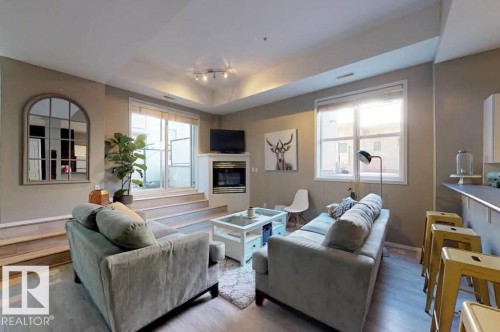 Living area featuring light wood-finish flooring and a corner fireplace - 109 10728 82 Avenue, Edmonton, AB - Indoor Photo Showing Living Room With Fireplace