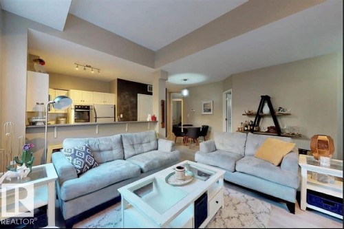 Open-concept living area featuring light-toned walls, recessed lighting, track lighting, a kitchen pass-through, and a dining area - 109 10728 82 Avenue, Edmonton, AB - Indoor Photo Showing Living Room