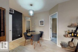 Dining area featuring wood-finish flooring, a contemporary pendant light fixture, an accent wall, and an open doorway - 