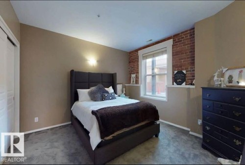 Exposed brick accent wall with a white-trimmed window - 109 10728 82 Avenue, Edmonton, AB - Indoor Photo Showing Bedroom