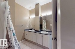 Dual vanity with white cabinetry, dark countertops, two integrated sinks, and individual wall-mounted lighting fixtures - 