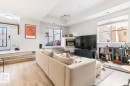 Spacious living area featuring wood-finish flooring, a contemporary fireplace with a brass-toned surround, and a large window providing ample natural light - 109 10728 82 Avenue, Edmonton, AB  - Indoor Photo Showing Living Room With Fireplace 