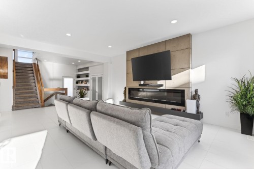 Living area featuring a floor-to-ceiling accent wall, an integrated linear fireplace, and recessed lighting - 793 Windermere Wynd, Edmonton, AB - Indoor Photo Showing Living Room With Fireplace