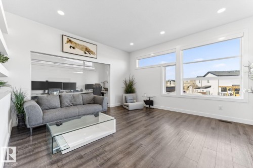 Spacious open-concept living area featuring wood-finish flooring and extensive natural light from multiple large windows - 793 Windermere Wynd, Edmonton, AB - Indoor Photo Showing Living Room