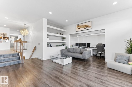 Bright living area featuring wood-finish flooring, recessed lighting, and an open concept office space with glass partitioning - 793 Windermere Wynd, Edmonton, AB - Indoor Photo Showing Living Room