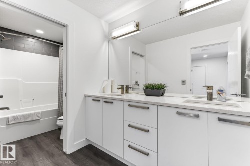 Bathroom featuring a double vanity with integrated sinks, white cabinetry, and brushed nickel hardware - 793 Windermere Wynd, Edmonton, AB - Indoor Photo Showing Bathroom