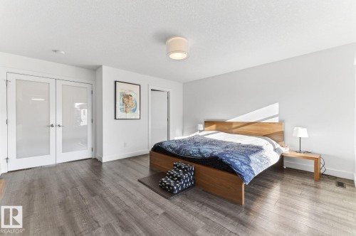 Spacious room featuring wood-finish flooring, white walls, and a contemporary ceiling light fixture - 793 Windermere Wynd, Edmonton, AB - Indoor Photo Showing Bedroom