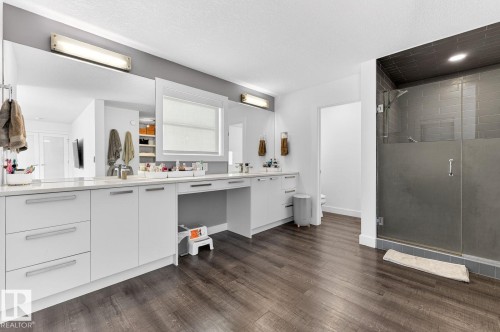 Contemporary bathroom featuring wood-finish flooring and a spacious vanity with white cabinetry and integrated sinks - 793 Windermere Wynd, Edmonton, AB - Indoor Photo Showing Kitchen