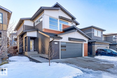 Contemporary two-story residence featuring a dark gray garage door with horizontal windows, a concrete driveway, and a covered entry - 793 Windermere Wynd, Edmonton, AB - Outdoor